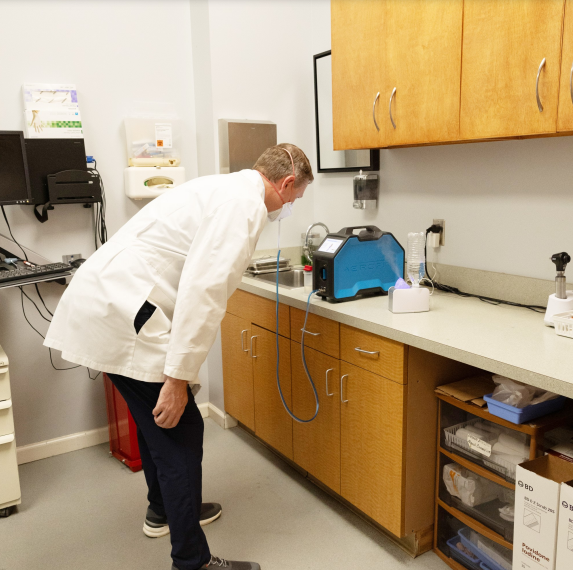 A man in lab coat looking at a device.