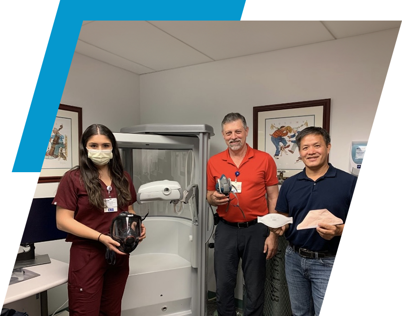 Three people standing in a room holding paper.